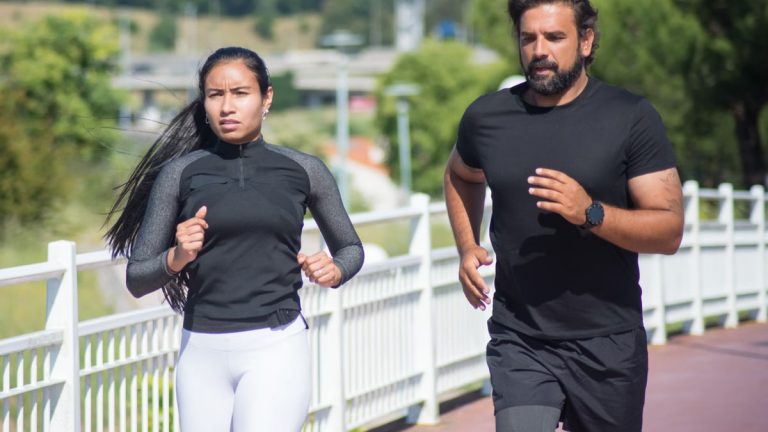 Active couple jogging outdoors on a sunny day, promoting fitness and healthy lifestyle.
